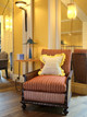 Cane armchair upholstered in Divide Terracotta with Wanderer Lemon cushion, blending earthy warmth and graphic texture in a modern social club setting. Designed by MBDS, photographed in the And Objects showroom.